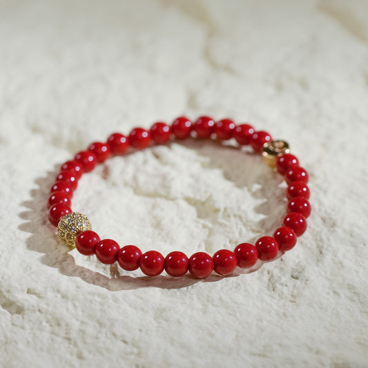 A stretch bracelet with red jasper beads, gold-plated CZ accent, and Gina Kim charm. Symbol of strength and vitality, handmade in Korea.
