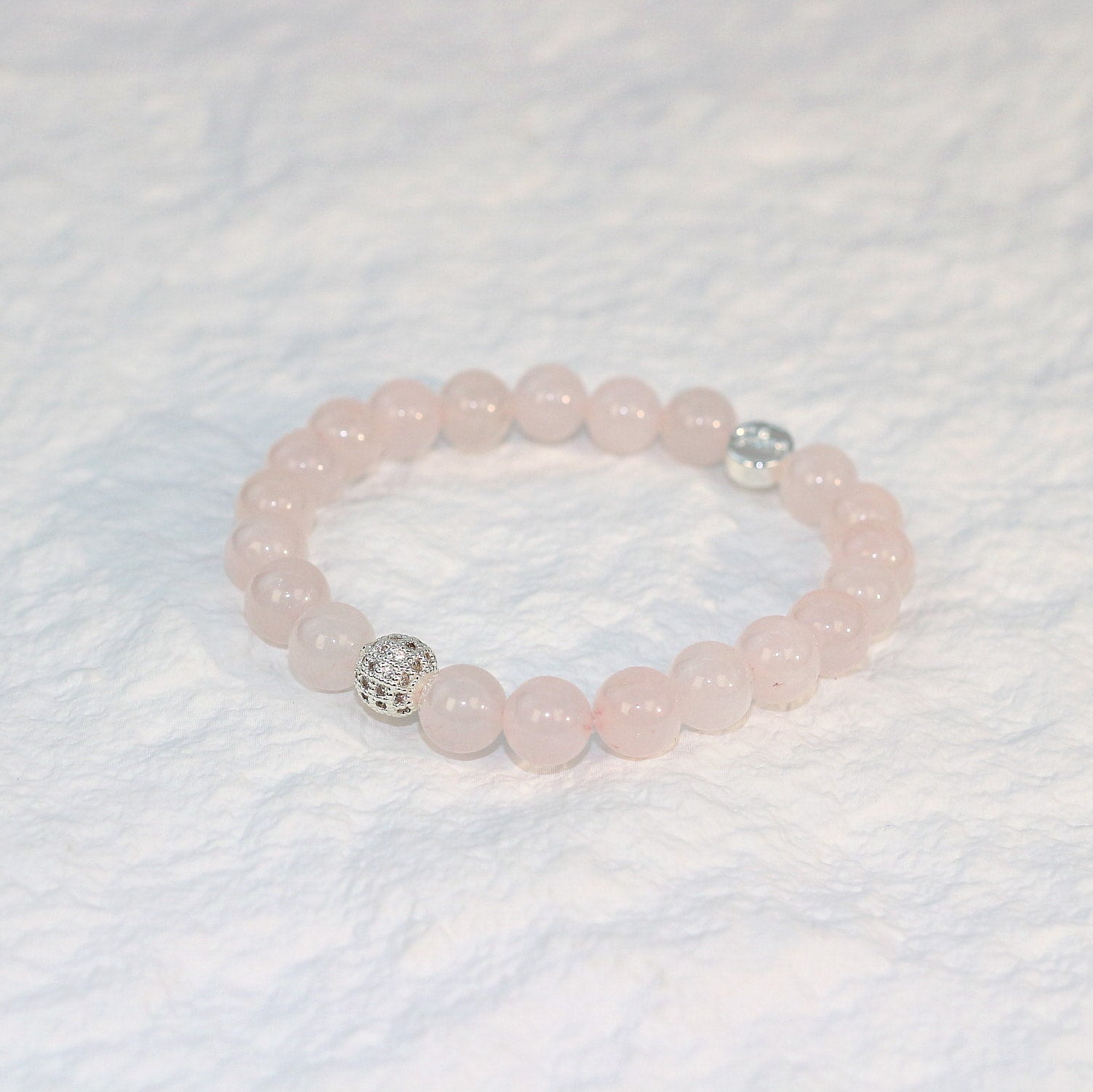 Front-facing image of the Rose Quartz Strength Bracelet showcasing soft pink hues and symmetrical arrangement on a clean display surface.