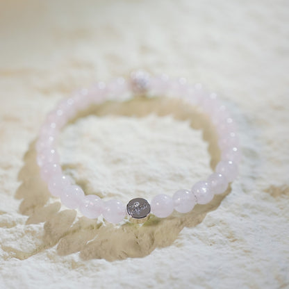 A stretch bracelet with soft pink rose quartz beads, gold CZ accent, and Gina Kim logo charm. Delicate and elegant.