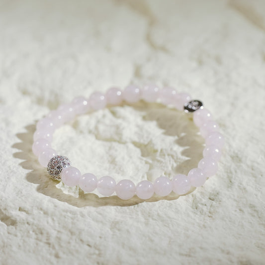 A stretch bracelet with soft pink rose quartz beads, gold CZ accent, and Gina Kim logo charm. Delicate and elegant.