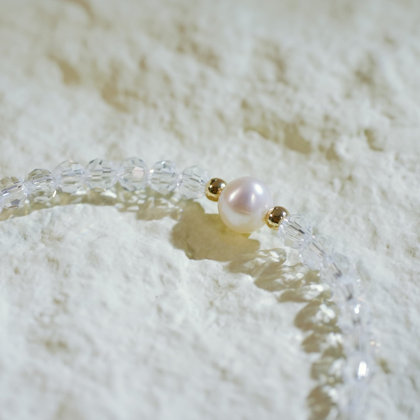 Close-up of the Silent Wish Bracelet showing sparkling quartz beads and a centered freshwater pearl, with gold-toned accents and GinaKimKR charm.