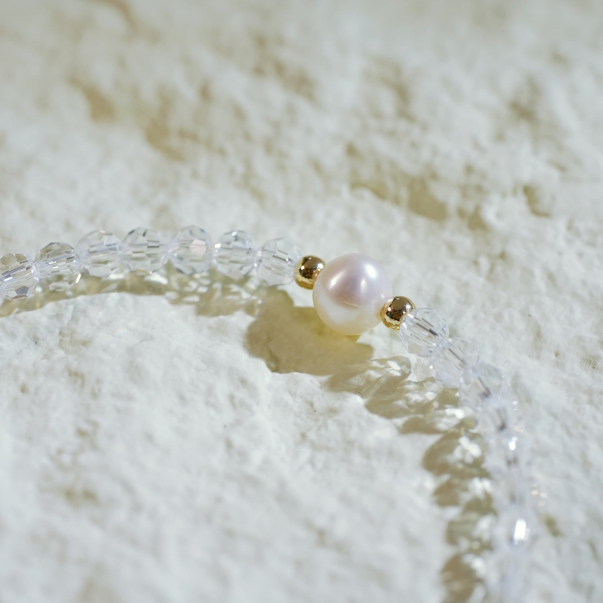 Close-up of the Silent Wish Bracelet showing sparkling quartz beads and a centered freshwater pearl, with gold-toned accents and GinaKimKR charm.