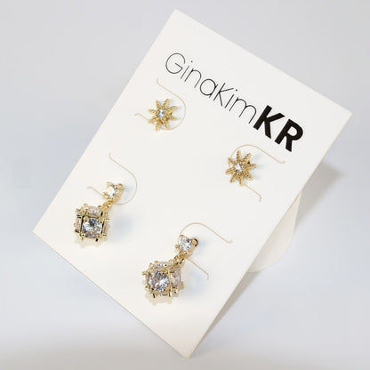 Top view of Starlume Earring Set with gold star studs and dimensional drop earrings, arranged on white card.