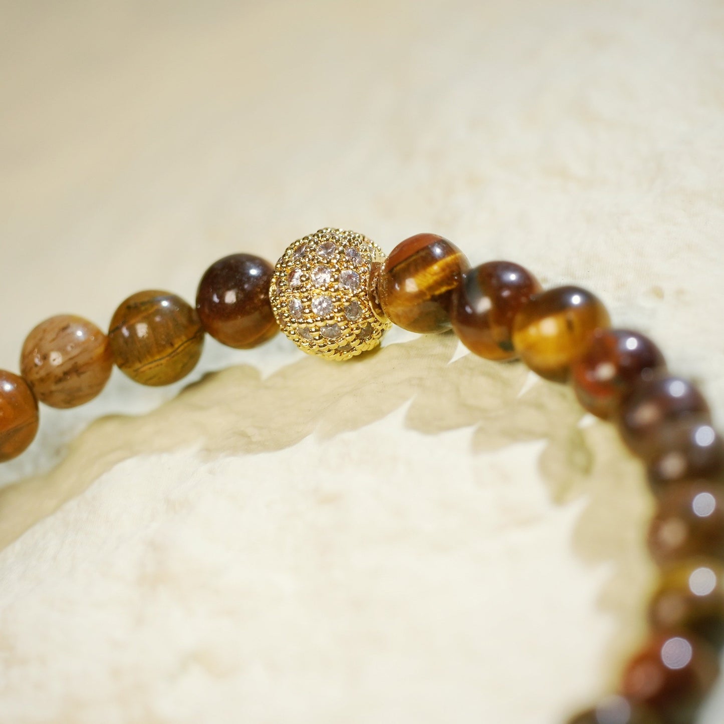 A stretch bracelet made with golden-brown tiger’s eye beads, gold-plated CZ accent, and Gina Kim logo charm. Grounding and empowering.