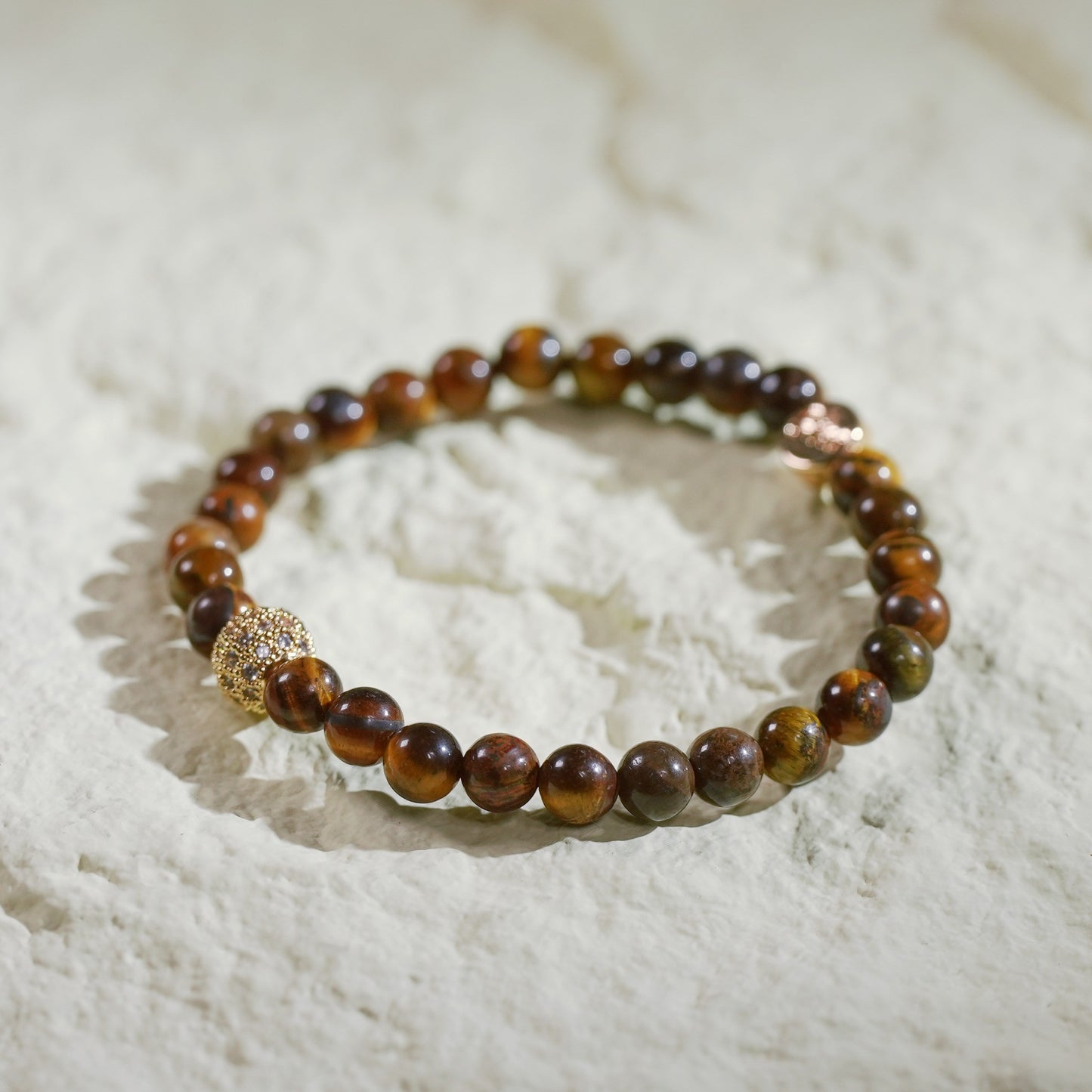 A stretch bracelet made with golden-brown tiger’s eye beads, gold-plated CZ accent, and Gina Kim logo charm. Grounding and empowering