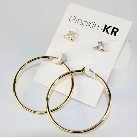 Triad Glow Earring Set shown in diffused daylight with triangle CZ studs and bold 42mm gold hoops, arranged on a soft cream product card.