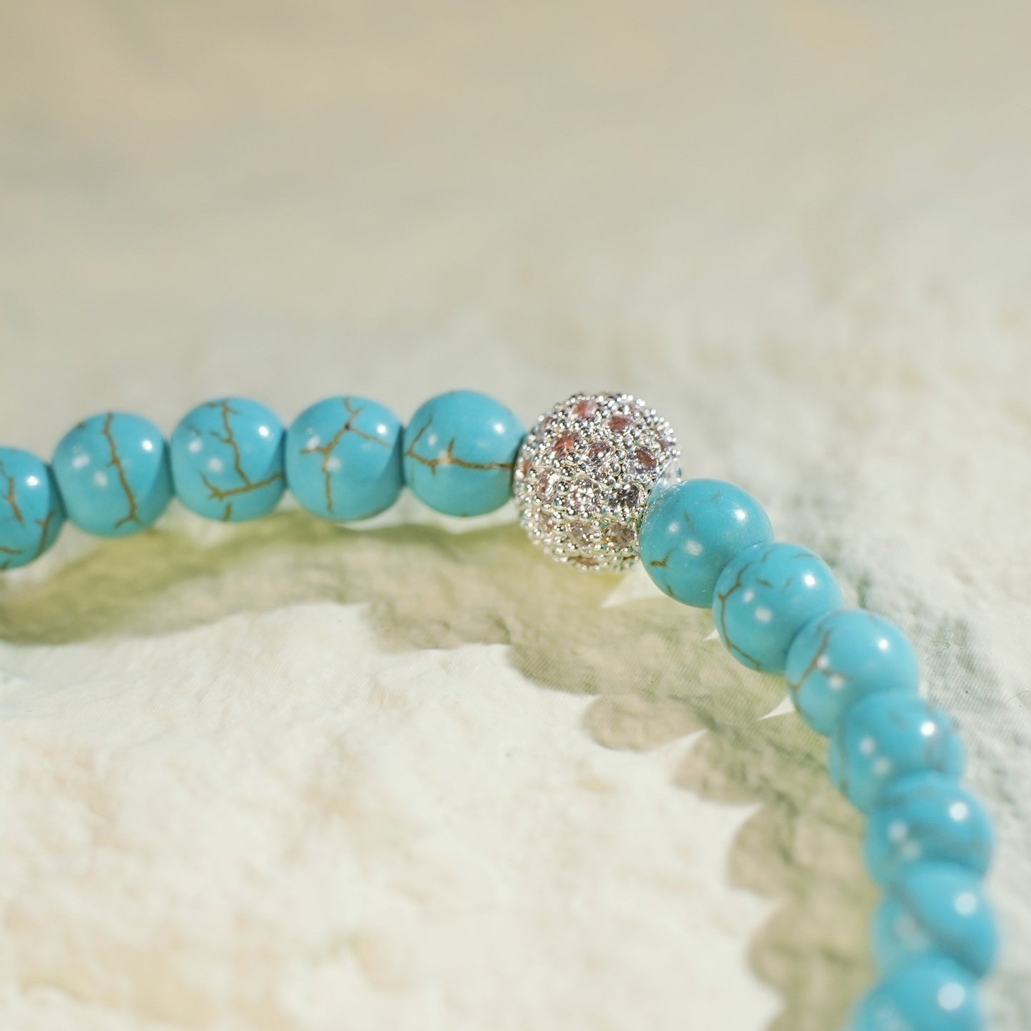 Close-up of the Turquoise Fortune Bracelet by GinaKimKR, highlighting vibrant turquoise stones, a gold CZ accent, and signature logo charm. Handcrafted and grounding.