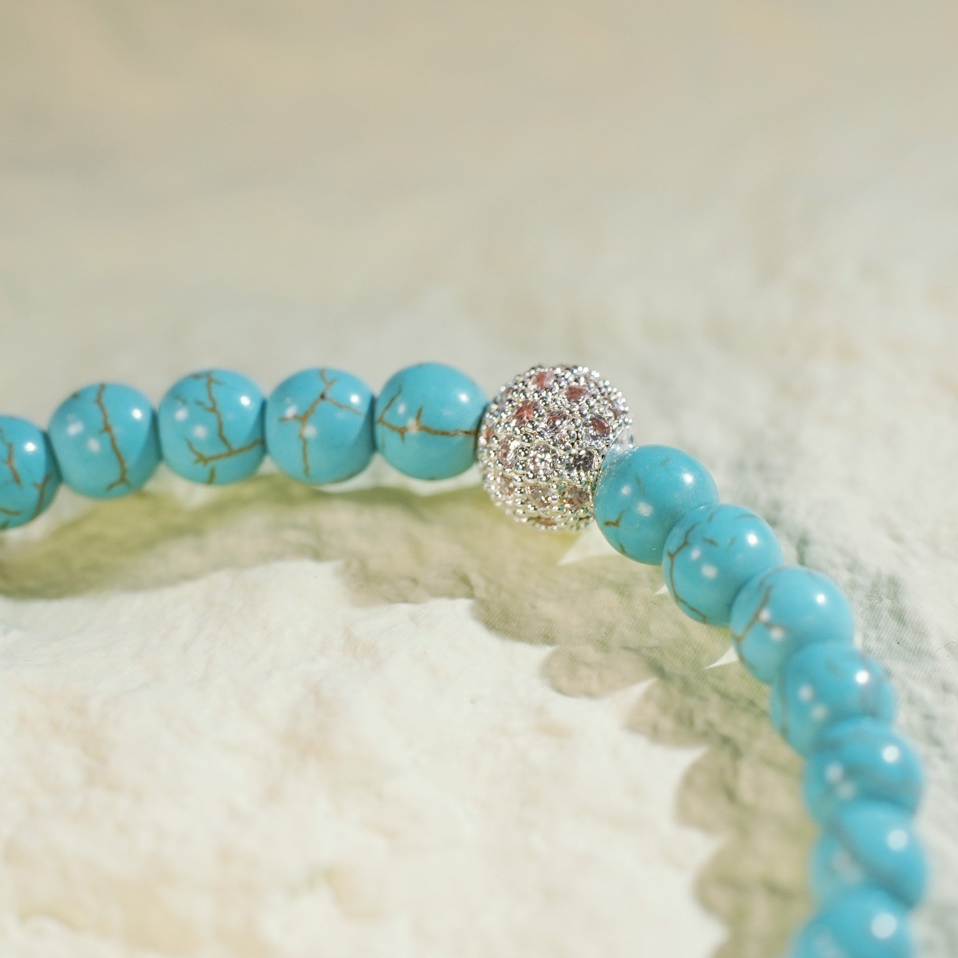 Close-up of the Turquoise Fortune Bracelet by GinaKimKR, highlighting vibrant turquoise stones, a gold CZ accent, and signature logo charm. Handcrafted and grounding.