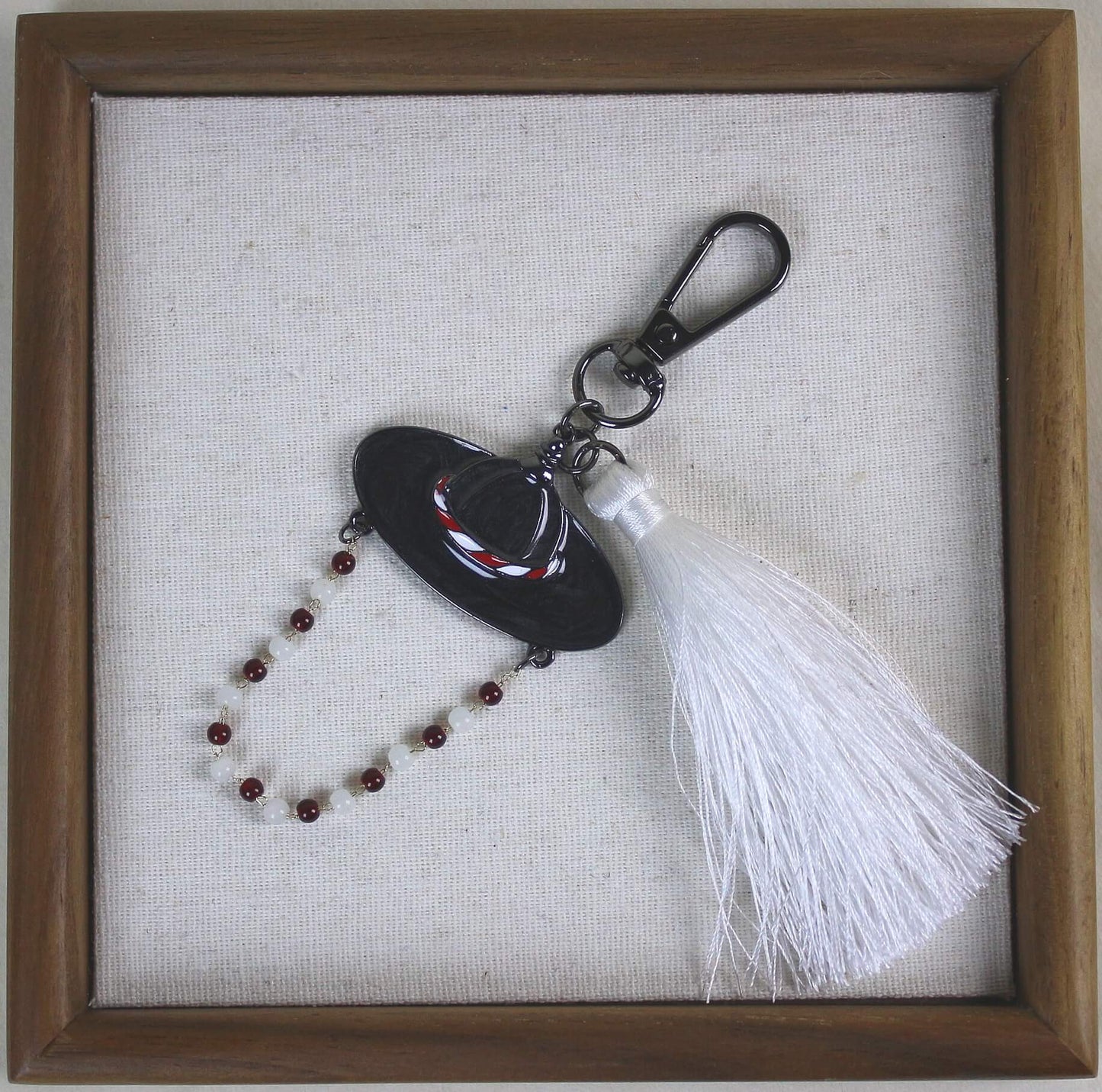 White Spirit Hunter Key Ring in a wooden frame, Korean heritage hat design with a white tassel and RUMI like K POP mood.