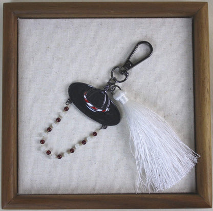 White Spirit Hunter Key Ring in a wooden frame, Korean heritage hat design with a white tassel and RUMI like K POP mood.