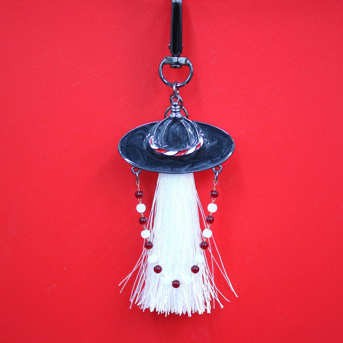 Close up of White Spirit Hunter Key Ring featuring a white tassel and Korean traditional hat shape with gentle glowing detail.