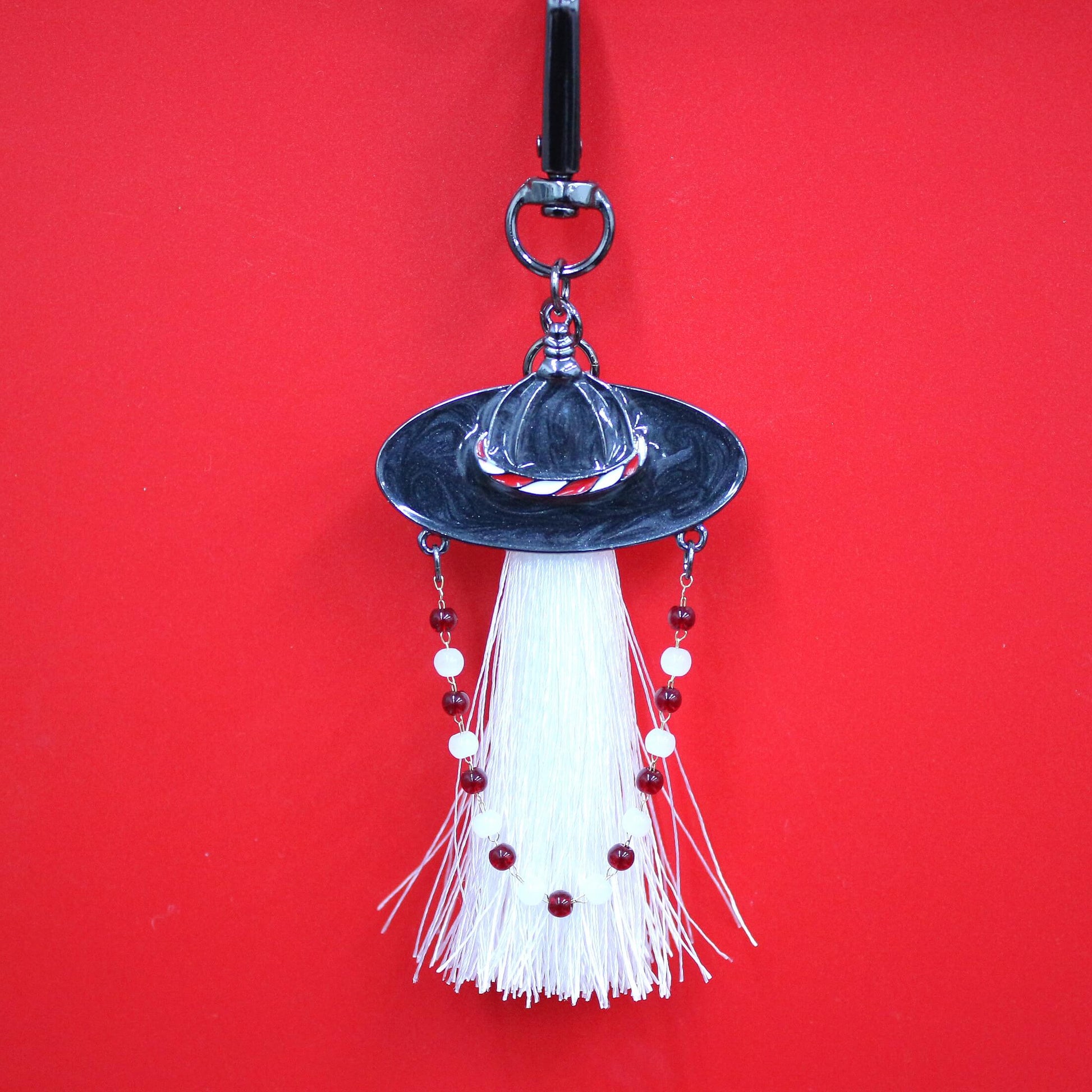 Close up of White Spirit Hunter Key Ring featuring a white tassel and Korean traditional hat shape with gentle glowing detail.